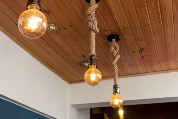three artesanal yellow light bulbes with wooden roof and blue & white paiting. Interior design...