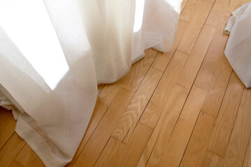Fototapeta na wymiar White cotton window textile touch wooden floor parquet with sun light into room cozy warm peaceful home eco house interior concept