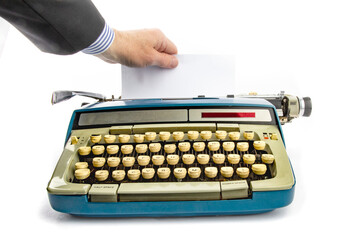 a business man hand pulling a sheet of paper from an old grungy manual portable typewriter with copy space
