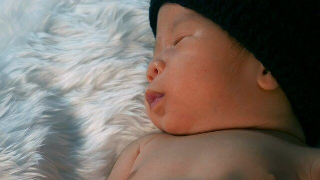 newborn baby in mouse costume sleeping on a fur bed