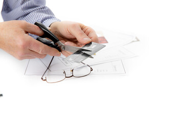a man's hand cuts an unidentified credit card with a pair of scissors isolated on white