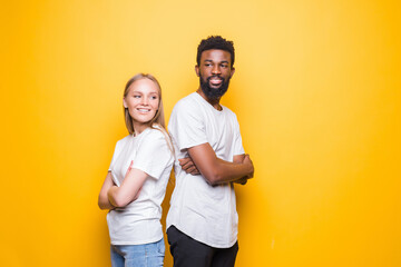 Portrait of happy multiracial couple hugging and posing together over yellow background