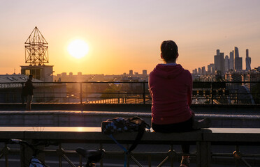 Fototapeta na wymiar girl is watching the sunset in the city