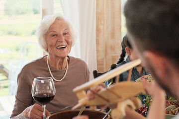 Senior woman smiling while she sitting at dinner table she happy for her son and his family