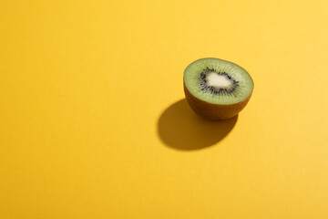 Half kiwi fruit over yellow desk with hard sunlight. Freshness concept. 