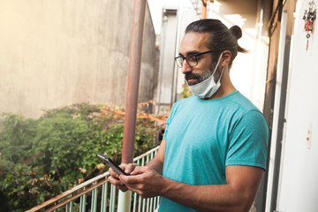 Man using the mobile and wearing the mask down in the face