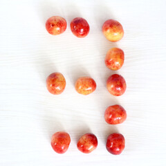 Fototapeta na wymiar number three from berries of sweet cherry on light surface, top view. sweet countdown 3