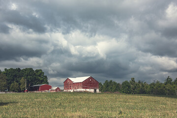 Red rural barn with heavy cumulus clouds overhead.