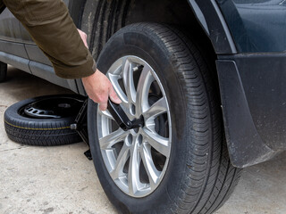 a man loosening the wheel nuts to replace a flat tyre