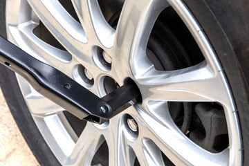 closeup of an auto manufacturer supplied tire wrench loosening a lug nut on a cast aluminum wheel