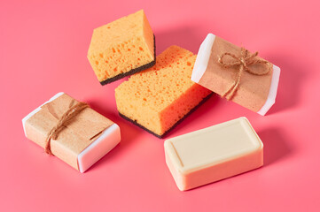 Scattered bricks of soap in vintage packing near sponges on pink background. Hygiene and cleaning concept