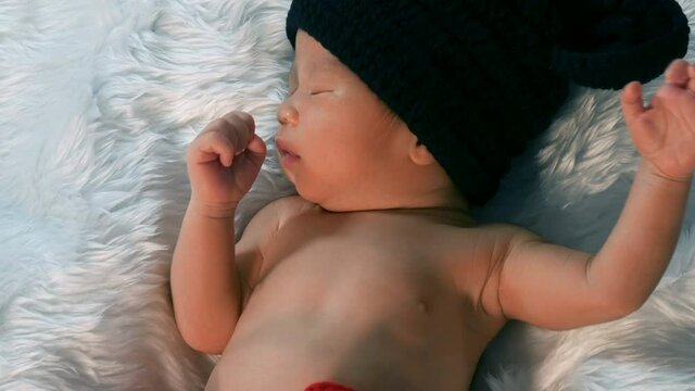 newborn baby in mouse costume sleeping on a fur bed