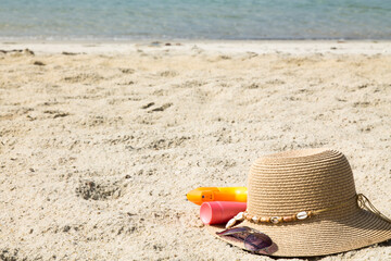 Fototapeta na wymiar hat, sunglasses and suntan lotion on the beach, summer vacation accessories