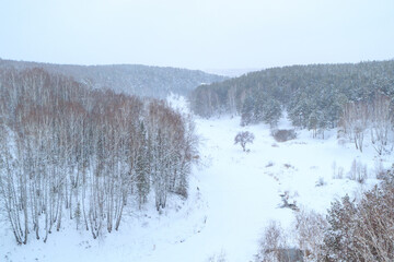 winter landscape from a high point to the frozen river and trees along the banks