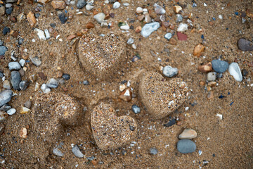 Blurred background with hearts figure from the sand in the summer beach. Selective focus on the hearts.