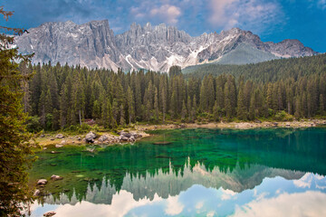 Lake Carezza an alpine lake surrounded with tall pine forest in the Dolomites with Rosengarten mountain range view background in South Tyrol, Italy