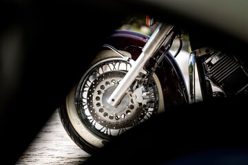 Selective focus shot of a wheel of a black motorcycle under the sunlight