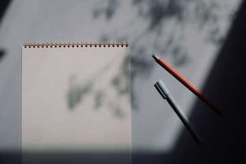 Blank sketchbook mock up, pen and pencil on shadow background, flat lay, top view.