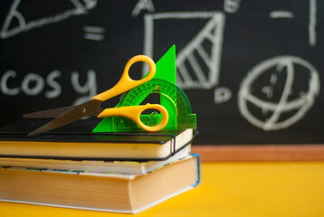 Back to school concept with books and colorful Stationery over black chalkboard. School times....