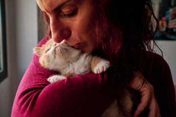 adult woman plays with orange kitten - pet care concept - Powered by Adobe