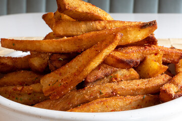 extreme closeup of a plate of crispy seasoned and coated French fried