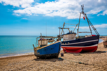 The view out to sea past fishing vessels moored on the beach at Hastings, Sussex, UK in summer