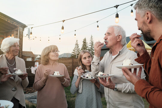 Big Family Standing In The Circle And Eating Cake Together During Party On Fresh Air