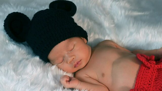 newborn baby in mouse costume sleeping on a fur bed