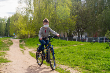 Boy rides a bicycle with a health mask due to the coronavirus pandemic