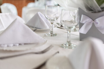 Mesa de convidados com forro branco, pratos, copos e guardanapos dentro dos pratos.