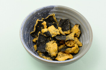 Chicken larb flavor seaweed tempura pieces in ceramic bowl on green background © merrimonc