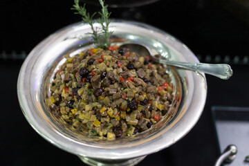 Vasilha de metal com antepasto de berinjela em mesa de buffet.