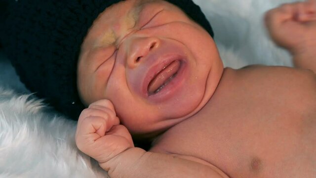 newborn baby in mouse costume crying on a fur bed