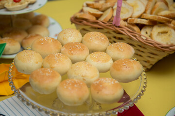 Porção de pães em bandeja em mesa de evento.
