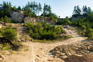 Limestone quarry landscape view. Hillside wall, dirt roads and some trees. Mine in Jozefow, Poland, Europe.