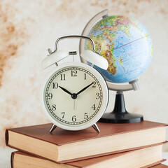 Alarm clock and globe on books. The concept of starting school, travel time.