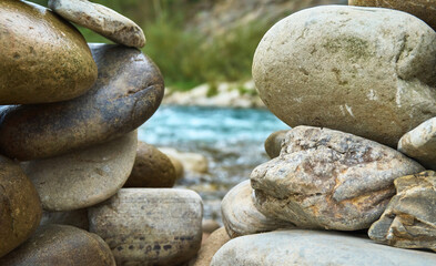 Stone cairn against the background of dark green water in. Stone balancing along the river.