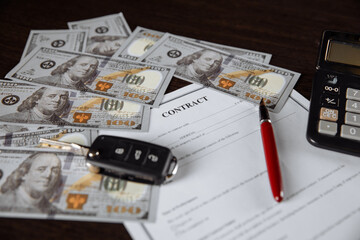 Car key and money on contract of car purchase on wooden table.