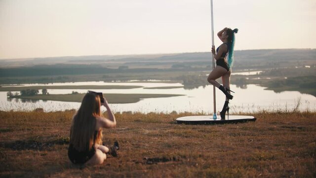 Woman taking photo of another woman standing by the dancing pole