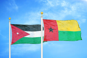 Jordan and Guinea-Bissau two flags on flagpoles and blue cloudy sky