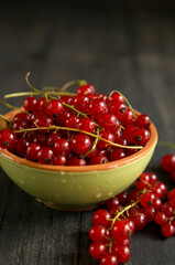 Red berry in a bowl on a dark wooden table.