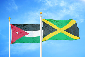 Jordan and Jamaica two flags on flagpoles and blue cloudy sky