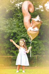 3-year-old birthday girl with her balloons outdoors