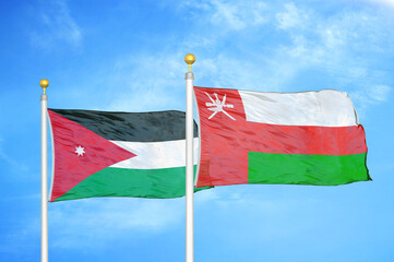 Jordan and Oman two flags on flagpoles and blue cloudy sky