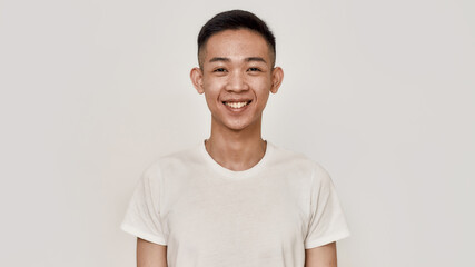 Smile. Portrait of young asian man with clean shaven face smiling at camera isolated over white background. Beauty, skincare, health concept