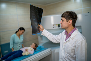 Fototapeta premium Mature male doctor looking at x-ray isolated on modern office backgound. Healthcare, roentgen, people and medicine concept.