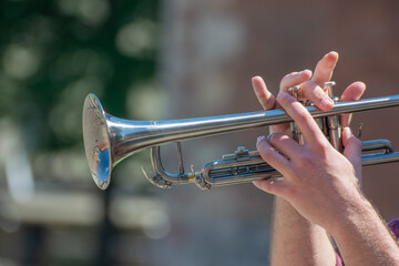 Hands of the musician playing a trumpet. close up musician with trombone on a public event.