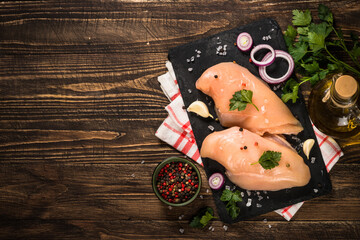 Chicken fillet with spices at wooden table.