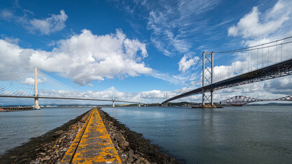 Obraz premium The Forth Bridges near Edinburgh in Scotland. Towering side by side over the Firth of Forth, these structures represent Scottish engineering over three centuries
