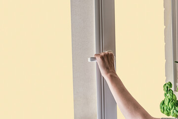 A woman's hand opens a window for airing room. window with curtain.